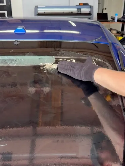 Installer squeegeeing window film by hand